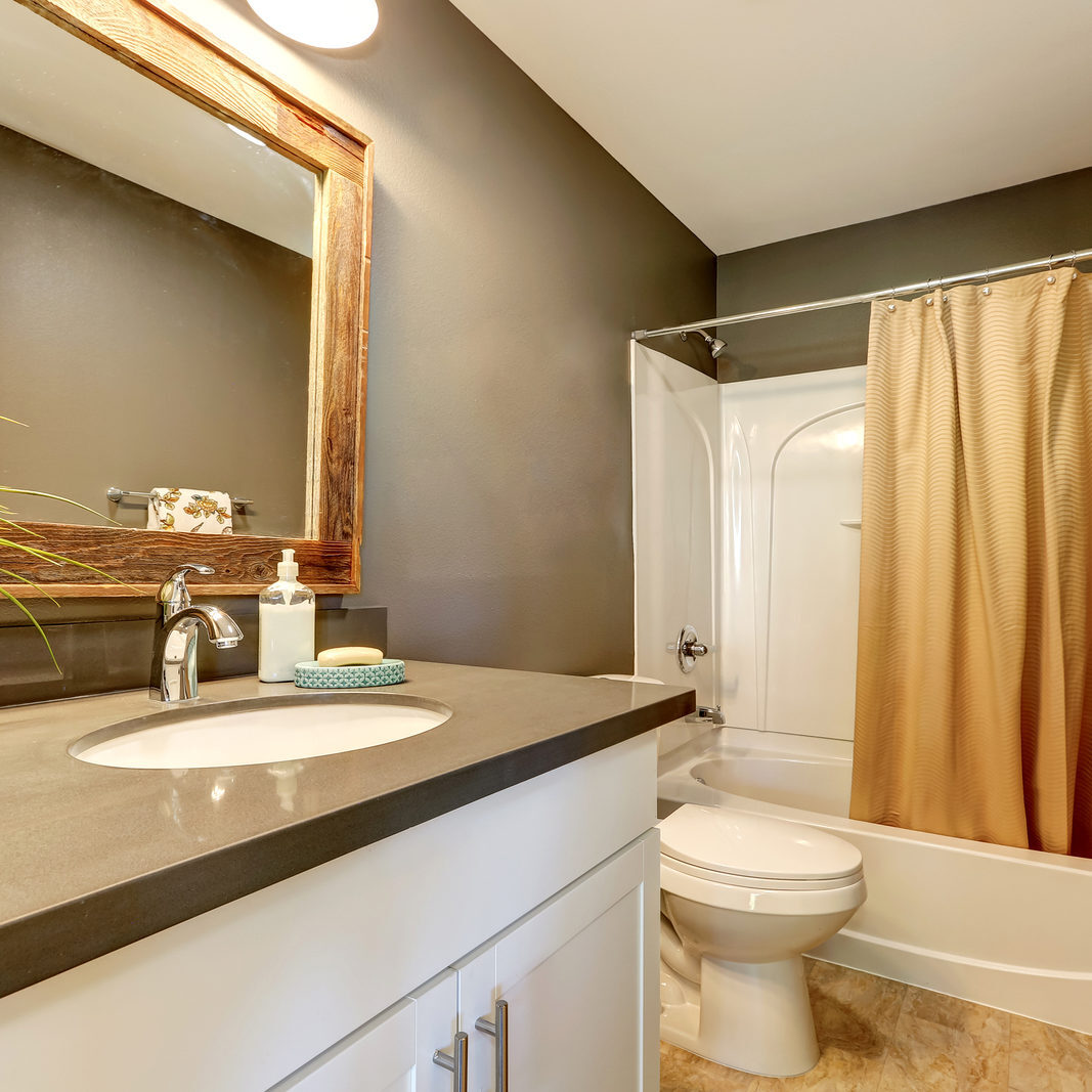 Interior of bathroom . Grey walls with white bathroom appliances. Has full bath shower with beige curtain toilet and vanity cabinet. Northwest USA